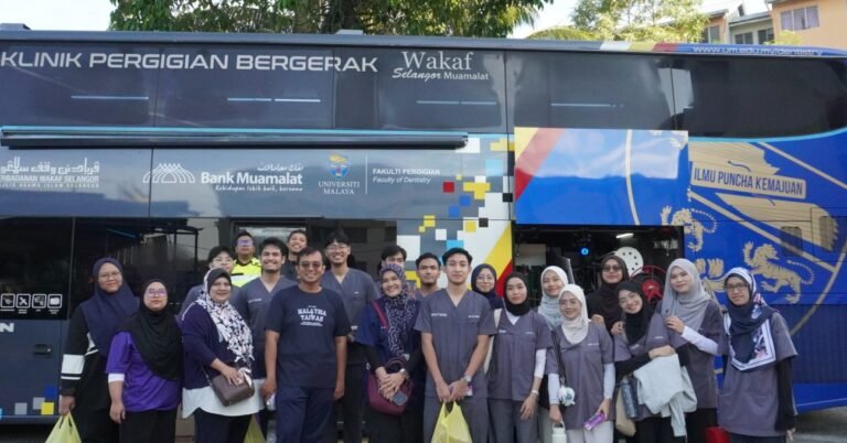 Sukarelawan UM bersama komuniti yang terlibat dalam pengajuran program di hadapan bas klinik bergerak pergigian